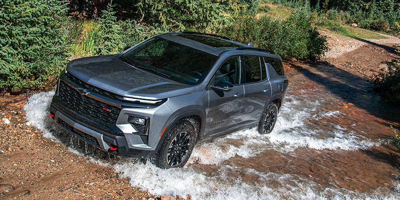 Grey SUV driving through a shallow, rushing stream.