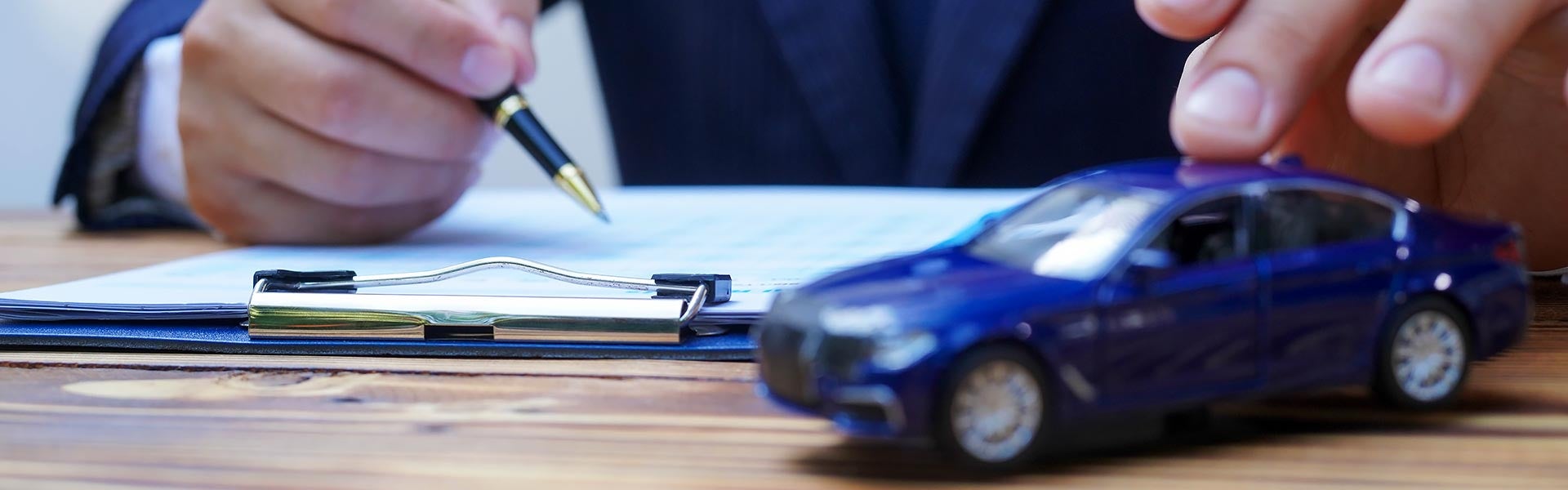 A blue toy car and person signin on paper
