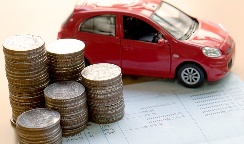 A red toy car and coins on paper